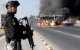 A member of the Prosecutor's Office stands guard near a burning bus at one of the main avenues after it was set on fire by organised crime groups in response to an operation in Jalisco to arrest a high-priority security target in Zapopan, state of Jalisco, Mexico, on February 22, 2026. Armed civilians blocked several roads in the state of Jalisco, in western Mexico, following an operation by federal forces in the town of Tapalpa, local authorities reported. Jalisco, which will host four matches of the upcoming 2026 World Cup, is home to the powerful Jalisco New Generation Cartel (CJNG), and has been rocked by several episodes of violence in recent years. (Photo by Ulises Ruiz / AFP)