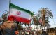 Un hombre sostiene una bandera iraní frente a personas que portan banderas de otros países.