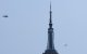 Two helicopters fly near the Empire State Building in New York on July 1, 2026. Two people climbed to the top of the Empire State Building on July 1 and unfurled a banner appearing to read "when the power of love beats the love of power the world knows peace," video published by US media showed. (Photo by TIMOTHY A. CLARY / AFP)