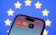 Una bandera de la Unión Europea detrás de las aplicaciones de AliExpress, Temu y Shein