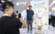 Un visitante y un robot humanoide hacen gestos de corazón mientras posan para fotos durante la Conferencia Mundial de IA 2026, en Shanghái.