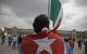 Una persona con una bandera cubana frente a la bandera de México (Archivo)