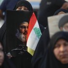 Una mujer sujeta un retrató del líder de Hezbolá Nasrallá junto a una bandera libanesa