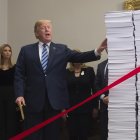 El presidente de Estados Unidos, Donald Trump, sostiene unas tijeras doradas mientras se prepara para cortar una cinta roja atada entre dos pilas de papeles que representan las regulaciones gubernamentales de la década de 1960 y las regulaciones de hoy (R) después de hablar sobre los esfuerzos de su administración en la desregulación en la Sala Roosevelt de la Casa Blanca en Washington, DC, 14 de diciembre de 2017