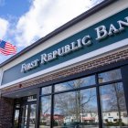Sede del banco First Republic Bank vista desde afuera. Hay un cartel con el nombre del banco escrito en letras blancas sobre fondo verde. También puede verse una bandera norteamericana.