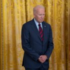 El presidente Biden parado frente a una cortina dorada.