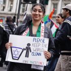 Una manifestante en Londres sostiene un cartel que muestra la bandera de Israel en un tacho de basura con un cartel que dice "por favor mantenga el mundo limpio" y "liberen a palestina.