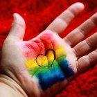 Mano de un niño pintada con los colores de la bandera LGBT y un corazón.