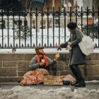 Una mujer entrega una ayuda a un homeless