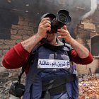 A reporter wearing a flak jacket with the hashtag in Arabic, "#Shireen Abu Akleh" takes a picture inside a house that was burnt during an Israeli military raid in the West Bank city of Jenin, on May 13, 2022. A Palestinian was wounded by Israeli fire during an operation in the northern occupied West Bank city of Jenin, Palestinian news agency Wafa said. (Photo by JAAFAR ASHTIYEH / AFP)