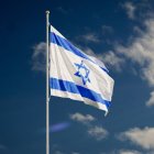 Bandera del estado de Israel flameando contra un cielo azulado con pocas nubes.