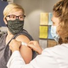 Médica poniendo una curita sobre el brazo de una mujer a la que acaba de vacunar.