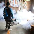 Un empleado del Ministerio de Salud fumiga una casa en Perú para enfrentar la crisis del dengue.
