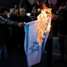 Manifestantes pro Palestina queman una bandera de Israel.