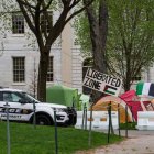 Un coche patrulla de la policía se encuentra junto a tiendas de campaña y carteles que llenan Harvard Yard