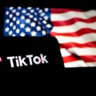 Un smartphone con el logo de TikTok delante de una bandera de los Estados Unidos.