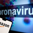 Logotipo de Amazon en un teléfono móvil con un modelo ilustrativo del coronavirus en un monitor de fondo. El crédito de la foto debe decir: James Warwick/EMPICS Entertainment