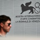 A man walks past the official logo of the 81th Venice Film Festival at Venice Lido, on August 27, 2024 on the eve of the opening ceremony. - With 21 films vying for the top Golden Lion prize, the 81st edition of the prestigious festival kicks off tomorrow, with Lady Gaga, Daniel Craig and Brad Pitt expected on the red carpet during the 10-day affair. (Photo by Marco BERTORELLO / AFP)