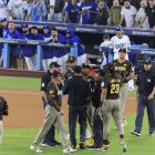 Los jugadores de los Padres de San Diego reciben instrucciones mientras que el Juego 2 de la NLDS del domingo 6 de octubre de 2024 se detiene debido a que los aficionados lanzan basura y pelotas de béisbol al campo en la 7ª entrada del partido entre los Dodgers de Los Ángeles y los Padres de San Diego en el Dodger Stadium de Los Ángeles, California. Jurickson Profar y Fernando Tatis hablan con los árbitros mientras les lanzan pelotas y basura.