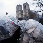 Personas desafían la lluvia bajo paraguas miran la catedral de Notre-Dame el día después de la reapertura de la emblemática catedral, en el centro de París, el 8 de diciembre de 2024.