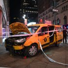 Un taxi accidentado, sni las partes delanteras del chasis, descansa en una zona acornada de una acera de Nueva York.