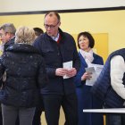 Friedrich Merz (CDU, centro), presidente del partido y candidato a canciller, habla con un ciudadano mientras deposita su voto junto a su esposa Charlotte Merz (2ª por la derecha) en el colegio electoral de Schützenhalle Arnsberg-Niedereimer.