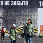 Un grupo de personas pasa junto a una pancarta gigante de "Izar una bandera sobre el Reichstag".