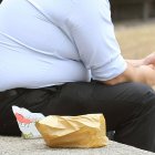 Una persona obesa comiendo una hamburguesa