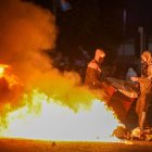Manifestantes enmascarados avivan una hoguera durante manifestaciones antiinmigración en Ballymena