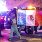 Manifestantes caminan junto a alguaciles con la bandera mexicana