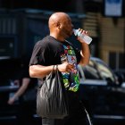 Un hombre bebe agua mientras cruza una calle en New York City, 2025.