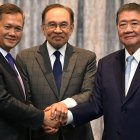 Malaysia's Prime Minister Anwar Ibrahim (C), Cambodia's Prime Minister Hun Manet (L) and Thailand's acting Prime Minister Phumtham Wechayachai (R) pose for photos as they shake hands following a press conference after talks on a possible ceasefire between Thailand and Cambodia in Putrajaya on July 28, 2025. Thailand and Cambodia began discussing a ceasefire in their festering border dispute on July 28, as the deadly skirmish dragged into a fifth day. (Photo by MOHD RASFAN / POOL / AFP)