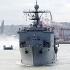 Una lancha de desembarco de colchón de aire (LCAC) sobrevuela la bahía de Elliott, detrás del buque de desembarco anfibio USS Rushmore (LSD 47), durante un desfile de barcos en conmemoración del centenario de la Gran Flota Blanca de Theodore Roosevelt. (Foto de la Marina de los EE. UU./Suboficial de segunda clase Jason Beckjord)