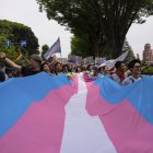 Una multitud carga una bandera transgénero