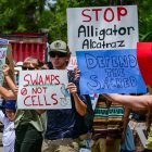 Manifestantes sostienen pancartas mientras protestan contra Alligator Alcatraz