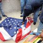 Un manifestante intenta quemar una bandera estadounidense que fue arrancada de un asta frente al Ayuntamiento de Baltimore el sábado 25 de abril de 2015, mientras continúan las protestas tras la muerte de Freddie Gray bajo custodia policial.