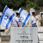 Two women carry the Israeli flag amid graves at a cemetary during the funeral of an Israeli soldier killed in the Gaza Strip