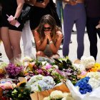 Una mujer se arrodilla y reza ante un monumento floral en memoria de las víctimas del tiroteo, frente al Pabellón Bondi en la playa Bondi de Sídney, el lunes 15 de diciembre de 2025, un día después del tiroteo.