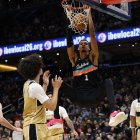 El alero de los San Antonio Spurs, Victor Wembanyama (1), clava el balón mientras el alero de los Washington Wizards, Kyshawn George (18), y el base de los Wizards, Bub Carrington (7), observan el segundo cuarto en el Capital One Arena.