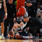El pívot de los Denver Nuggets, Nikola Jokic (15), se agarra la rodilla izquierda mientras el entrenador David Adelman se acerca a él tras una lesión contra los Miami Heat durante el segundo cuarto en el Kaseya Center.