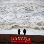 People look at the waves while standing behind a warning sign reading "Danger" (Files)