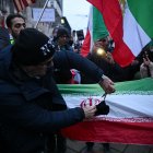 Un manifestante corta la bandera de la República Islámica de Irán