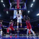 Jaylon Tyson (20), de los Cleveland Cavaliers, realiza un mate entre Joel Embiid (21) y VJ Edgecombe (77), de los Philadelphia 76ers, durante la primera mitad de un partido de baloncesto de la NBA el viernes 16 de enero de 2026 en Filadelfia.