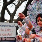 Una procesión pasa junto a una pancarta colocada contra la explotación sexual y la violencia contra las niñas