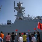 People wave Cuban and PRC flags as several Chinese Navy