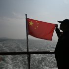 Un hombre sostiene una bandera china sobre un barco