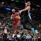 El base de los Philadelphia 76ers, V.J. Edgecombe (izquierda), realiza un pase mientras es marcado por el pívot de los San Antonio Spurs, Victor Wembanyama, durante la primera parte de un partido de baloncesto de la NBA, el lunes 6 de abril de 2026, en San Antonio.