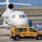 Pasajeros con trajes protectores azules abordan un avión tras ser evacuados del crucero MV Hondius