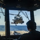 Un marinero estadounidense observa cómo un MH-60R Sea Hawk, adscrito al Escuadrón de Ataque Marítimo en Helicóptero (HSM) 51, despega de la cubierta de vuelo del destructor lanzamisiles de la clase Arleigh Burke USS Rafael Peralta (DDG 115) mientras patrulla el mar Arábigo para hacer cumplir un bloqueo marítimo contra los buques que entran o salen de los puertos y zonas costeras iraníes, el 12 de mayo de 2026. El Rafael Peralta está desplegado en la zona de operaciones de la 5.ª Flota de EE. UU. para apoyar la seguridad y la estabilidad marítimas en Oriente Medio. (Foto de la Armada de EE. UU.)