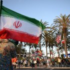 Un hombre sostiene una bandera iraní frente a personas que portan banderas de otros países.